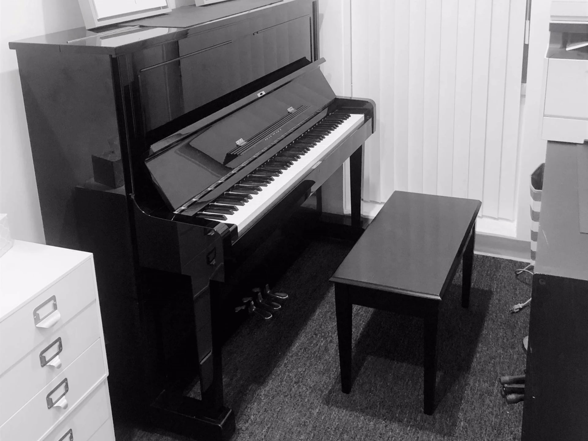 Black upright piano in an Issimo practice room